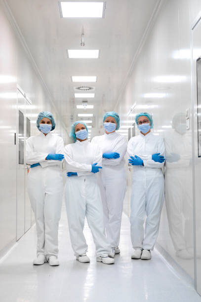 Fully equipped female workers seen standing in the hallway of the pharmaceutical factory stock photo