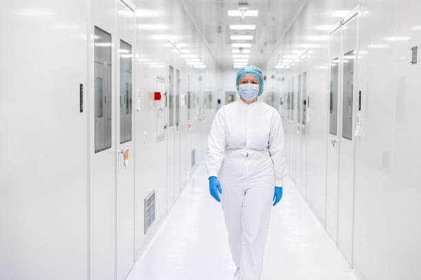 istock Female worker in pharmaceutical laboratory seen wearing protective equipment while walking down the hallway 1405217456
