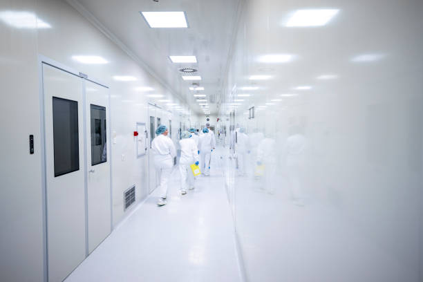 Workers in protective equipment in the pharmaceutical industry seen on shift in the hallway of the production plant stock photo