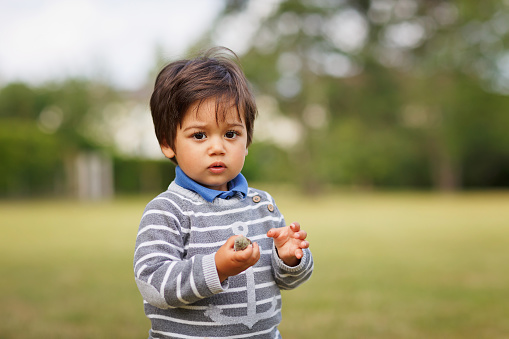 Portrait of a little eastern handsome baby boy playing outdoor in the park. Arabian child fun on the street.