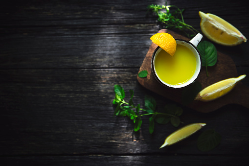 Homemade fresh lemon juice, shot from the top on a dark and burn wooden background with copy space.