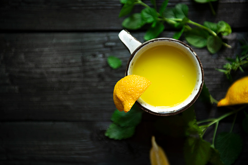Homemade fresh lemon juice, shot from the top on a dark and burn wooden background with copy space.