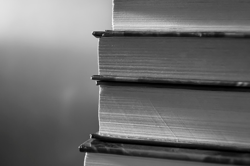 A stack of books is black and white photo. A close stack of books. Books in grey tones.