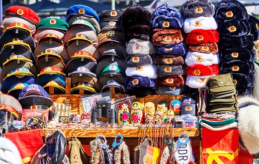 Berlin, Germany, June 21, 2022: Caps, hats and souvenirs with the insignia of the Soviet Union and the German Democratic Republic at a stall near Checkpoint Charlie