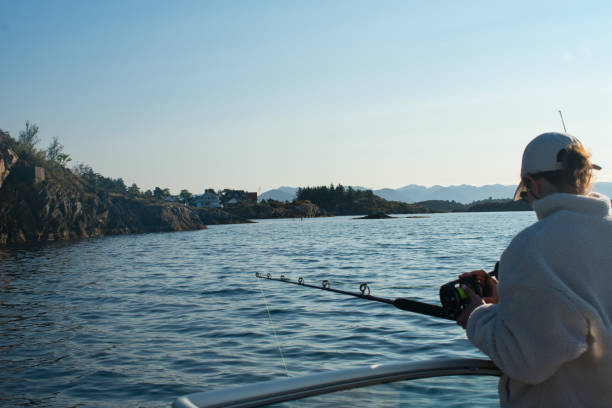 female fisherman with fishing rod on a boat in the ocean near stavanger norway (jig fishing) - recreational boat nautical vessel fishing rod motorboat imagens e fotografias de stock