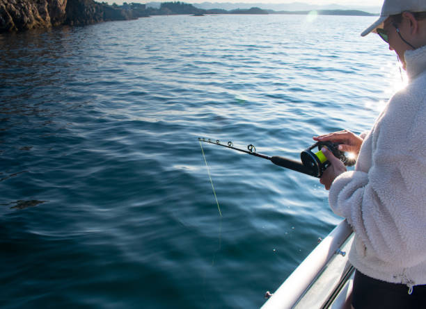 female fisherman with fishing rod on a boat in the ocean near stavanger norway (jig fishing) - recreational boat nautical vessel fishing rod motorboat imagens e fotografias de stock