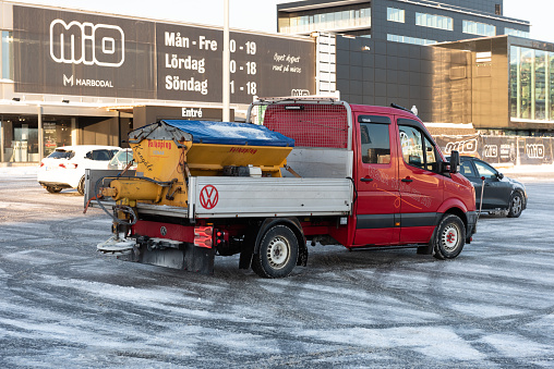 Gothenburg, Sweden - december 04 2021: Small truck preading salt and sand on a parking lot.
