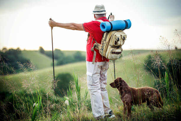 istock Senior  man hiking while and dog follows him 1405239120