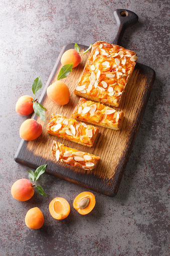 Sweet apricot biscuit with almonds close-up on a wooden board on the table. Vertical top view from above