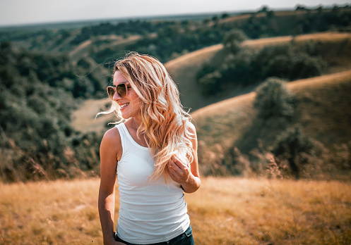 Cheerful smiling woman outdoor enjoys the hilly landscape