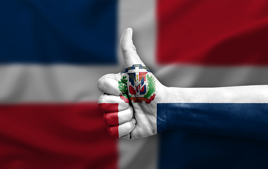 Hand making thumb up painted with flag of dominican republic