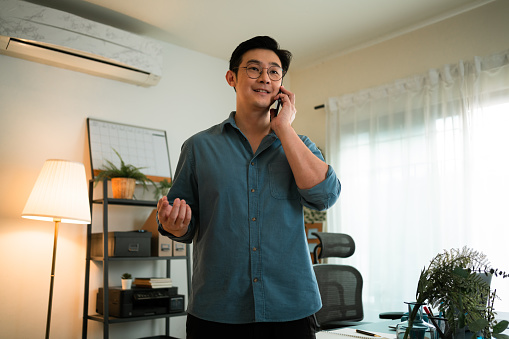 Smiling Asian Man explaining investing plan to his clients on the cell phone