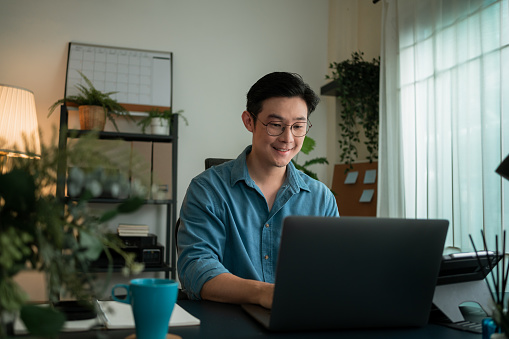 Feliz y sonriente Hombre escribiendo correo electrónico a su cliente. Tiene una reunión virtual en línea en una computadora portátil en casa. photo