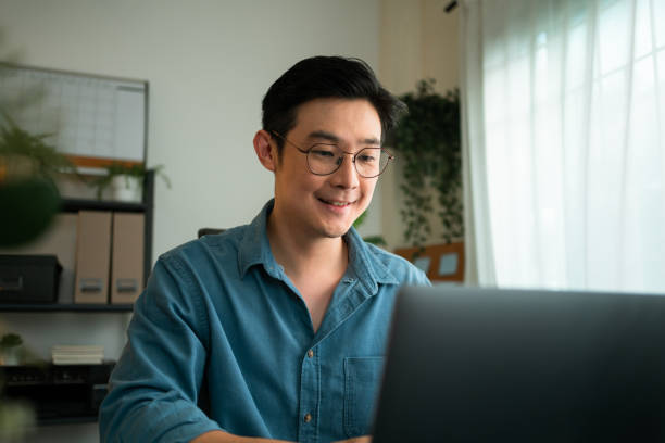 istock Close-up smiling Man Typing looking on laptop computer. He has online virtual meeting on laptop computer at home. 1405243329