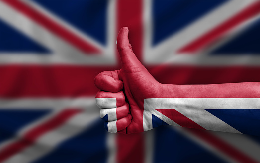 Portrait of man at the studio with gray background. Concept with copy space. He is holding British flag in the hand