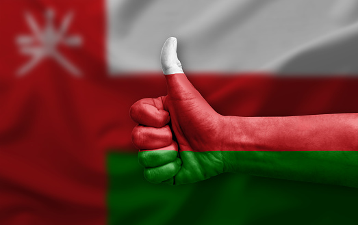 Hand making thumb up painted with flag of oman