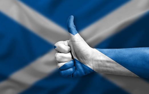 Hand making thumb up painted with flag of scotland