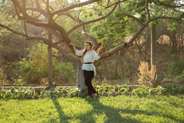 istock Young woman leaning against a plum tree. 1405247478