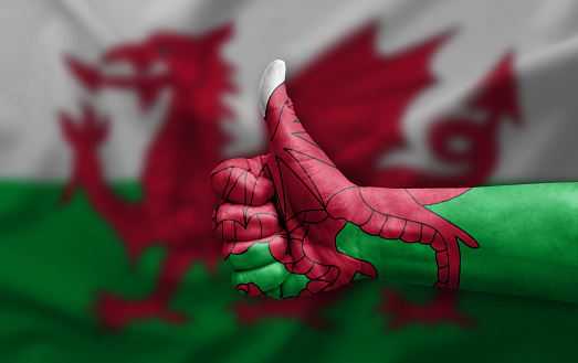 Hand making thumb up painted with flag of wales
