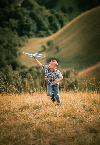 brother and sister play in nature with a kite and plane