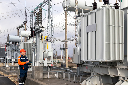 electrical engineer inspecting high voltage transformer at power plant