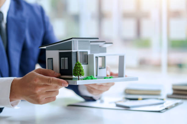 agente inmobiliario ofrece diseño y contrato de casas. aprobación de un contrato de compra o venta de una vivienda. ofrece préstamos hipotecarios y concepto de seguro de hogar. - compraventa casas fotografías e imágenes de stock