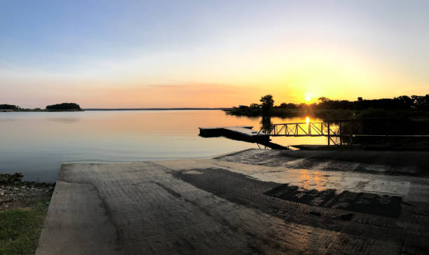 포도 나무 호수 해안 근처의 작은 파도를 파노라마로 볼 수 있으며 이른 아침 일출에 막대 홀더에 낚싯대가 서 있습니다. - boat launch 뉴스 사진 이미지