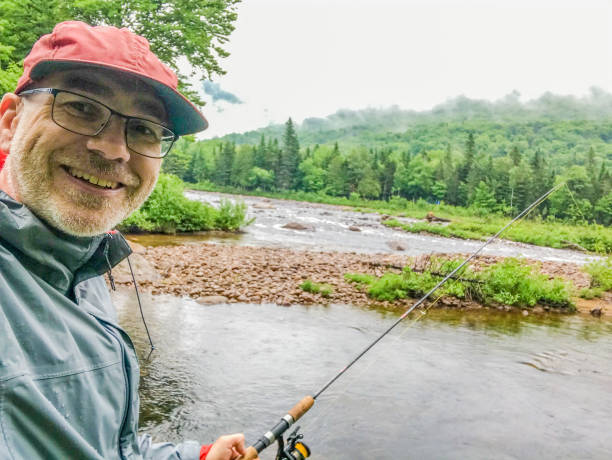 Mature man happy to fish on river stock photo