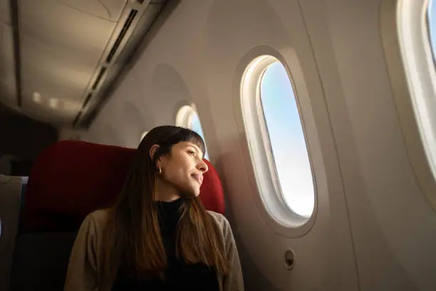 Photo of Young woman traveling by plane looking out the window