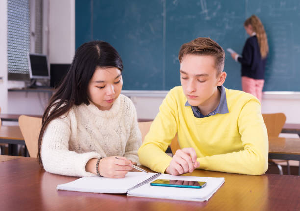 istock Asian teen girl explaining study material to classmate 1405264262