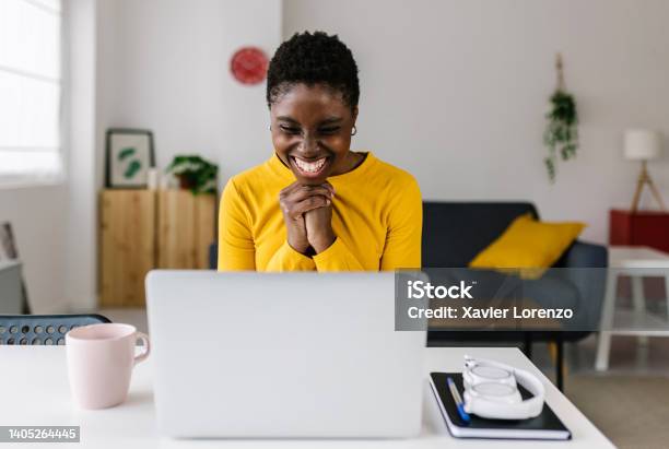 Excited Young African Woman Celebrating Success Looking At Laptop Screen Stock Photo - Download Image Now
