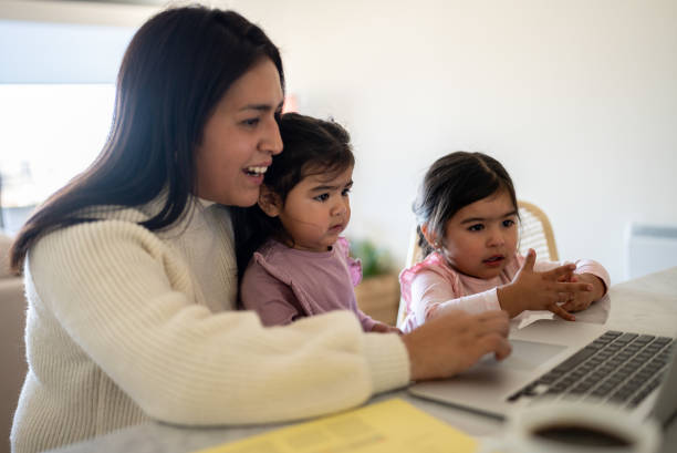 istock Mother using the laptop with daughters at home 1405265924
