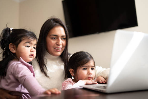 istock Mother using the laptop with daughters at home 1405265945
