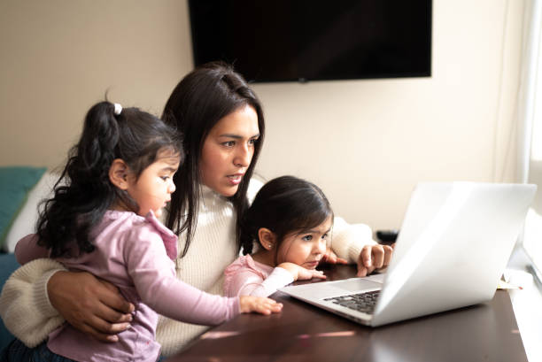 istock Mother using the laptop with daughters at home 1405265957
