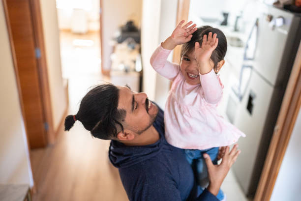 Father holding daughter at home