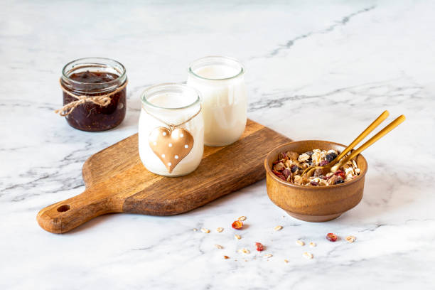 yogurt, jam and muesli on the marble kitchen table, couple breakfast concept