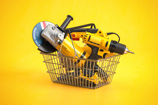 Shopping basket with elecric tools and construction equipment angle grinder, electric drill and jigsaw on yellow. Selling and buying online. 3d illustration