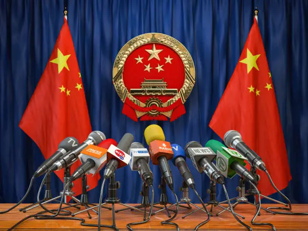 Photo of Official press conference of China fgoverment or president. Flags of China and microphones.