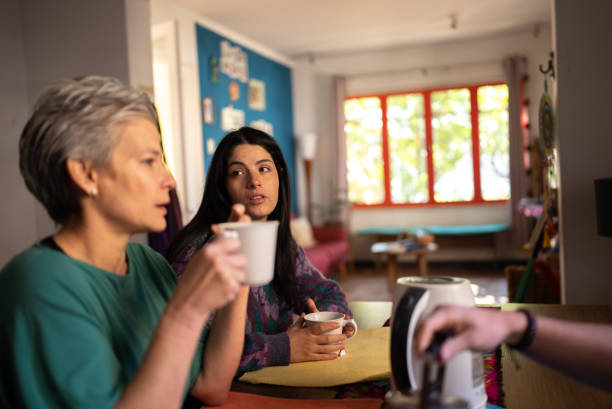 istock Mother and daughter talking while drinking coffee at home 1405267171