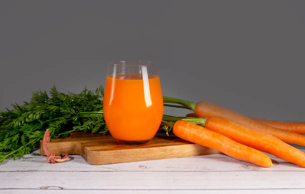 istock Fresh-squeezed carrot juice on wooden cutting board on white background 1405268330