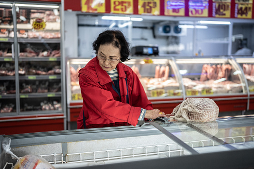 Senior woman buying frozen food in the supermarket