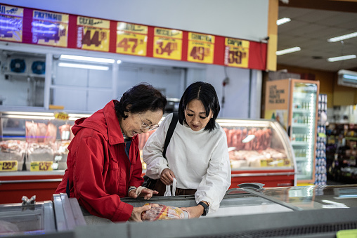 Mother and daughter buying frozen food in the supermarket