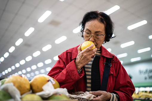 Senior woman choosing papayas in a supermarket