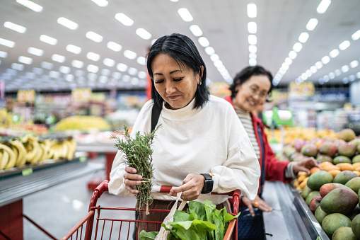 Mature woman holding rosemary in a supermarket