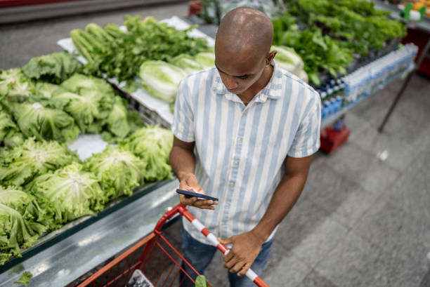 istock Young man using the mobile phone in a supermarket 1405275583