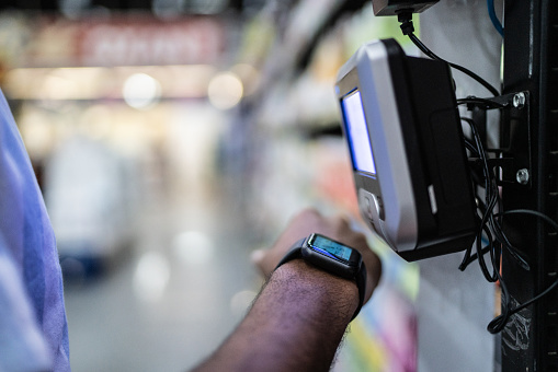 Young man paying with a smartwatch in a supermarket