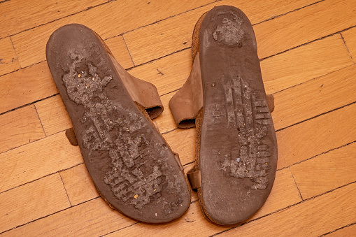 Old used dirty shoes soles on parquet floor