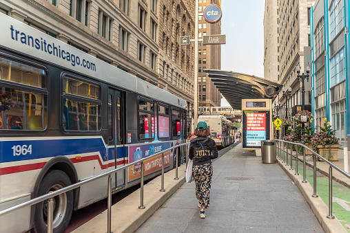 Chicago, IL - September 28, 2021: A young woman catches a CTA bus downtown, in the Loop.
