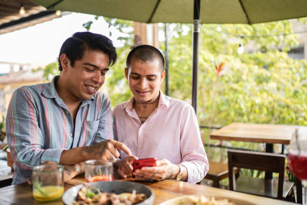 istock Gay couple using mobile phone at restaurant 1405281537