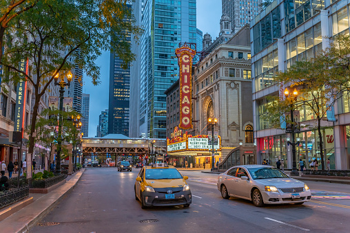 Chicago, IL - September 28, 2021: A taxi cab in focus downtown at night, with the Chicago Theater and the famous State Street beyond.